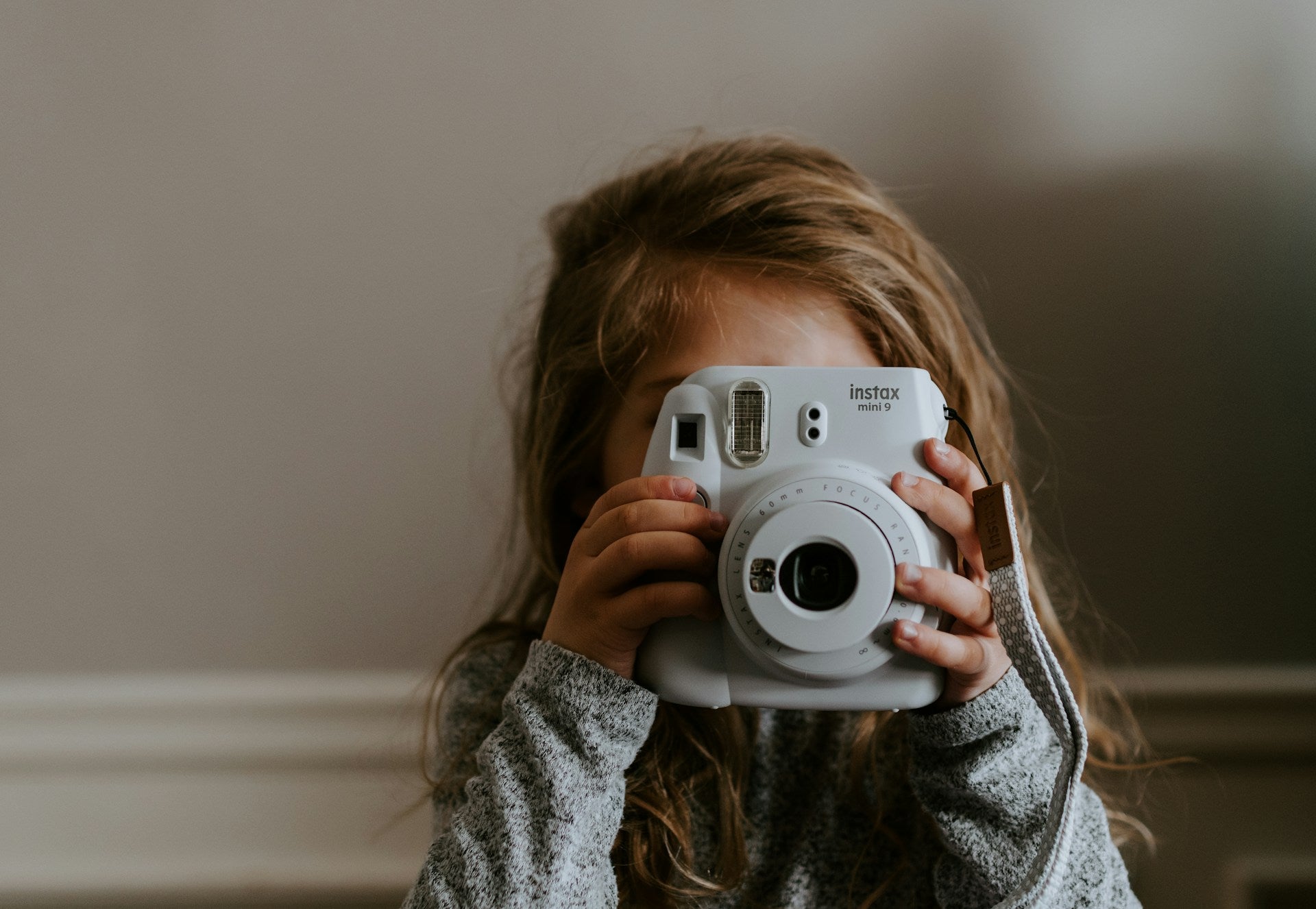 Young girl holding up polaroid camera.