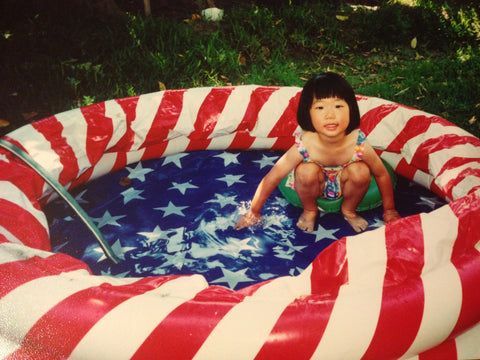 Cindy as a child on the Fourth of July in a USA flag inflatable pool