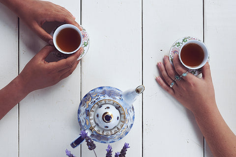 top-down photo of two full tea cups and a tea pot