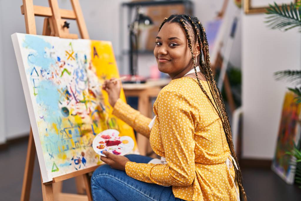 Smiling woman painting on stretch canvas