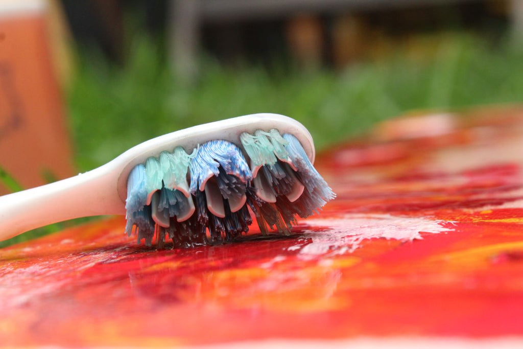 Toothbrush laying on canvas used for acrylic paint splatter technique