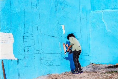 Person sketching design before beginning their wall mural outdoors