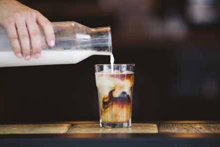milk being poured into a glass of ice and homemade cold brew