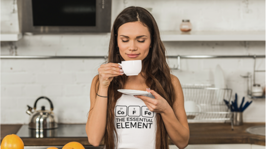 beautiful woman smelling the aroma from her coffee cup wearing a coffee the essential element tank top
