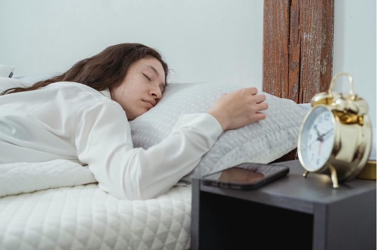 A young woman peacefully sleeping in bed, illustrating the importance of sleep in the weight loss journey.