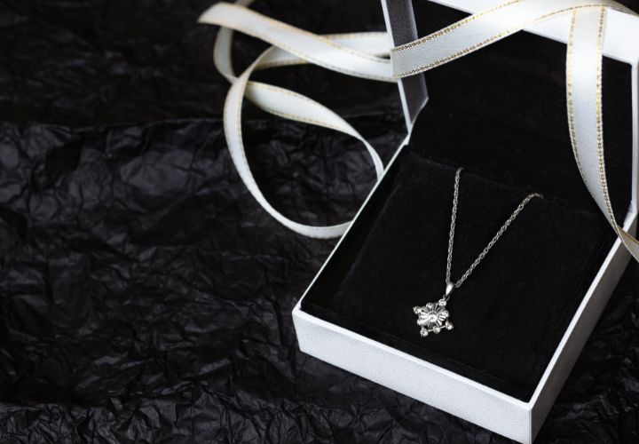 Silver necklace with custom pendant inside a white box that's on a black background.