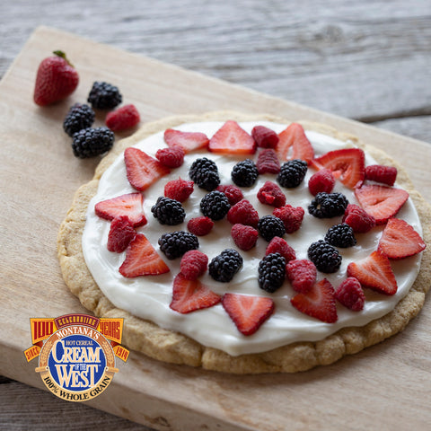 Cream of the West Roasted Wheat fruit pizza topped with blueberries, strawberries and raspberries and a cream cheese frosting.