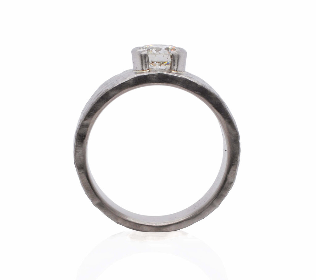 wide hammered white metal wedding ring with a raised white diamond in a half bezel and a crushed hammered texture.