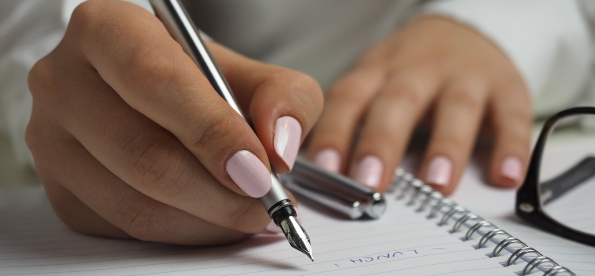 Close-up of a woman writing in a journal using a cartridge pen