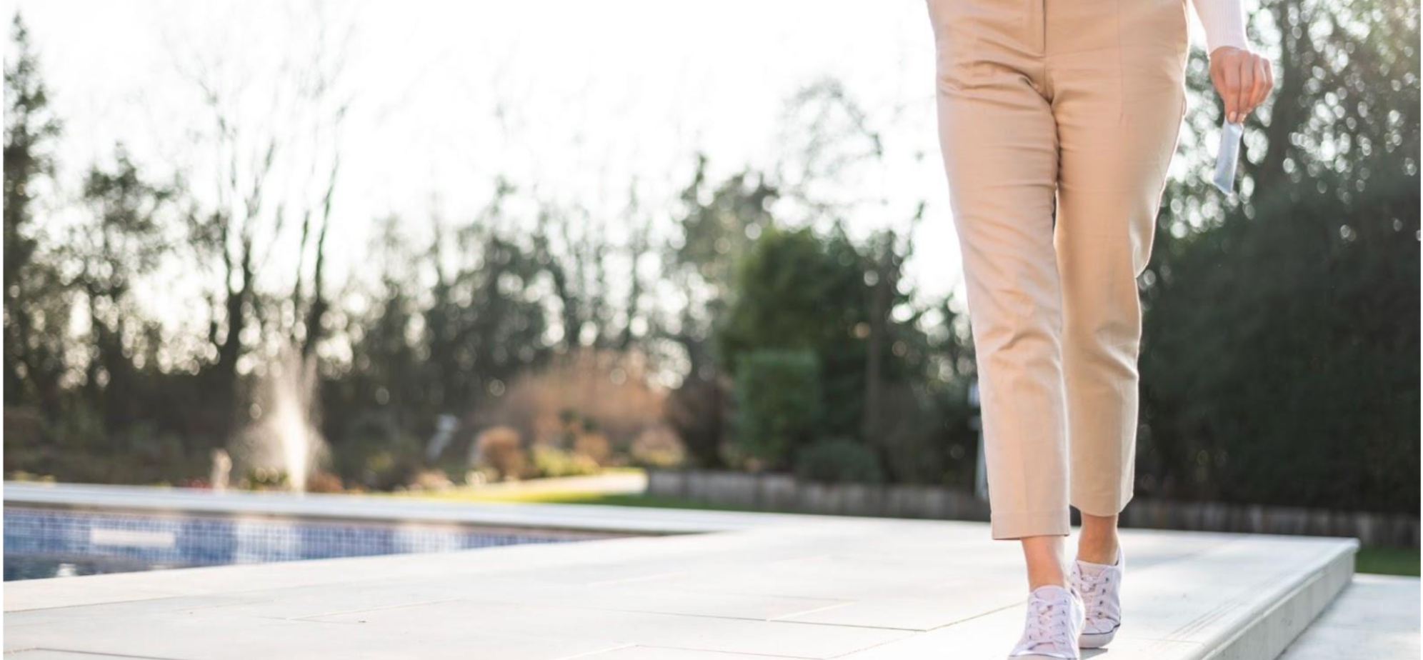 Close-up of woman’s legs walking, with her hand holding an Arella Beauty Collagen Supplement