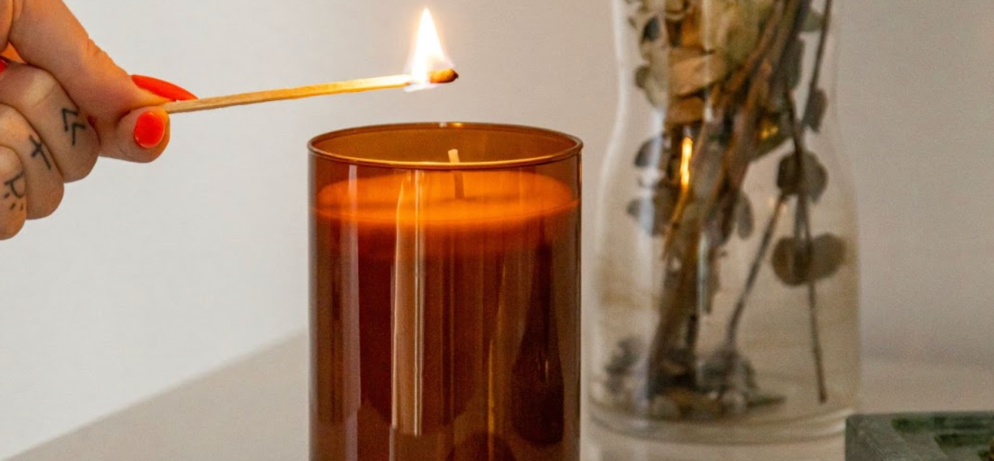 Close-up of woman’s hand lighting a candle with a match