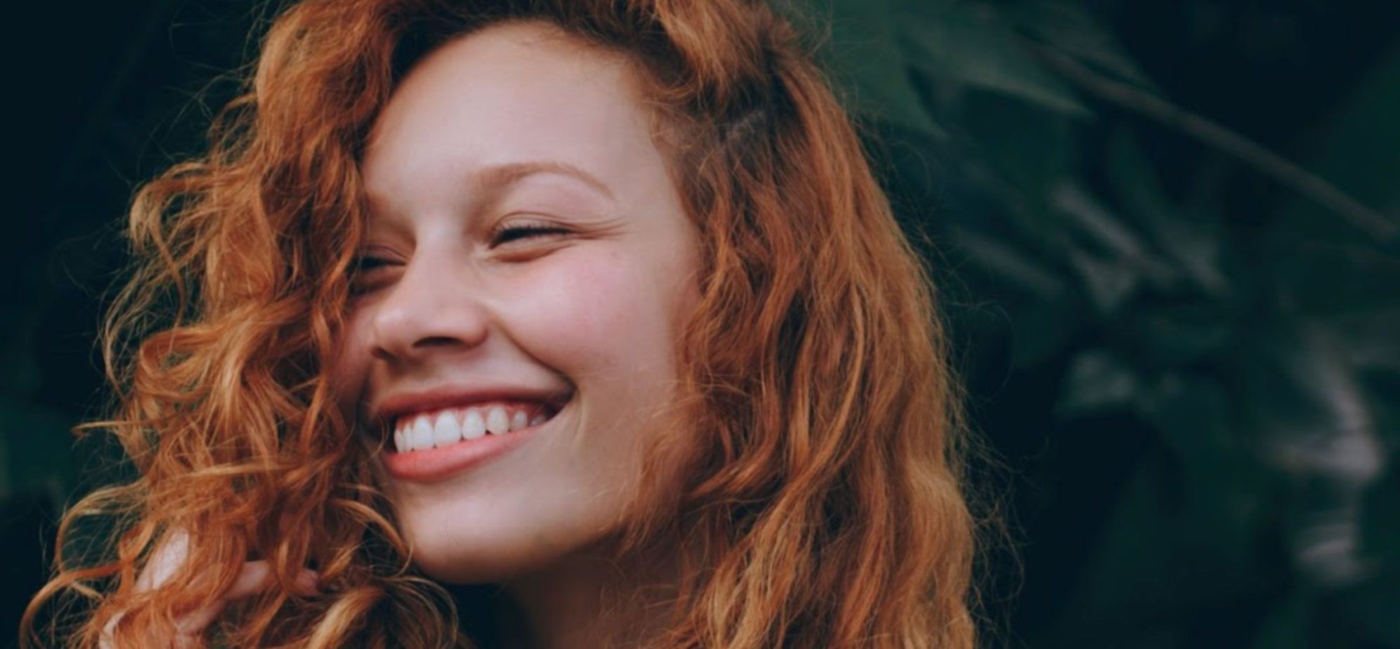 Woman laughing and smiling with long, curly red hair