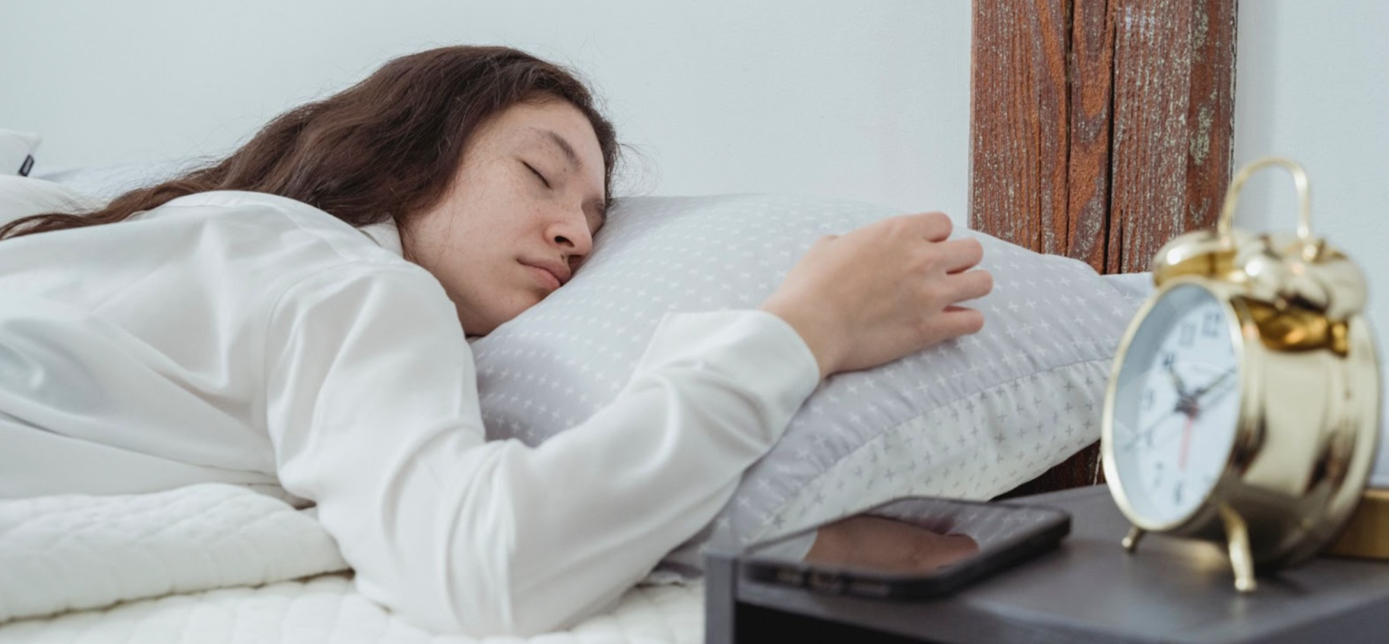 Woman sleeping in bed next to an alarm clock