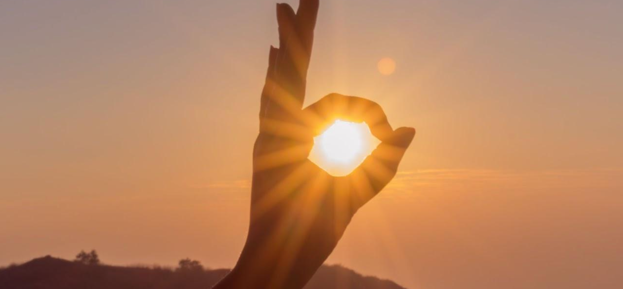 Person’s hand outlining the winter sun.