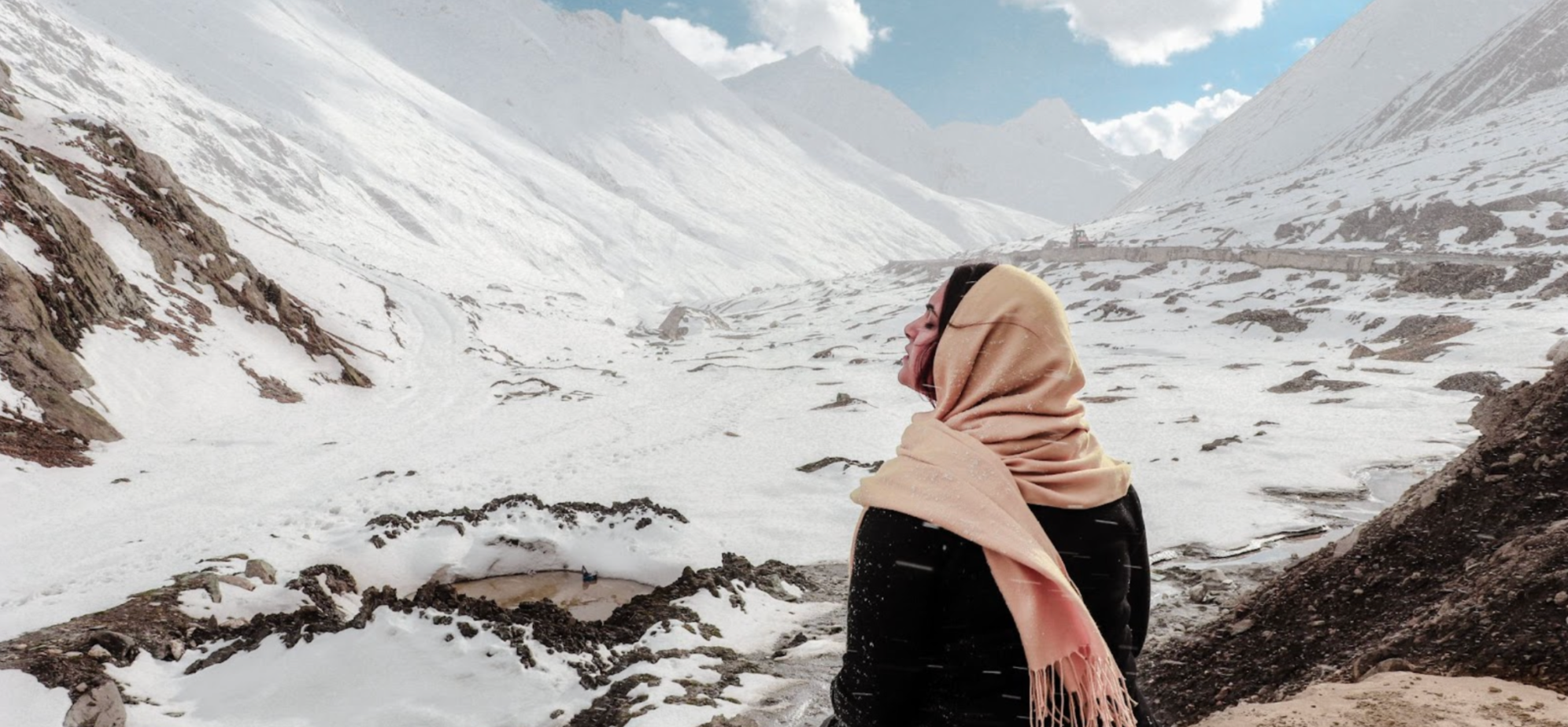 Woman sitting on top of snow-capped mountains in winter