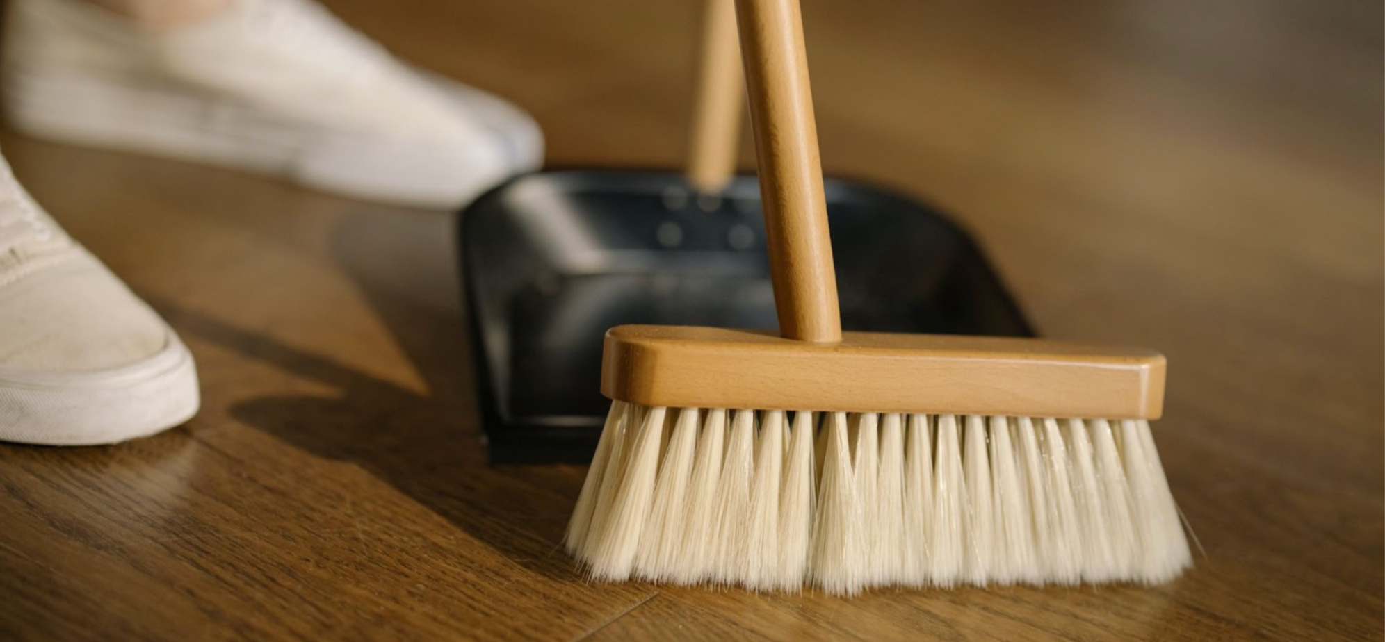 Close-up shot of woman sweeping and cleaning with a wooden broom