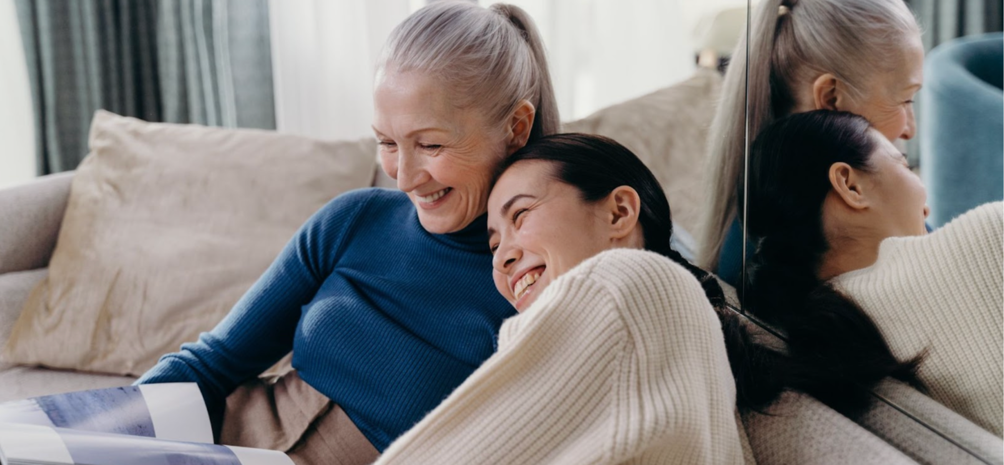 Smiling mother and daughter, an older woman with grey hair and a younger woman with dark hair