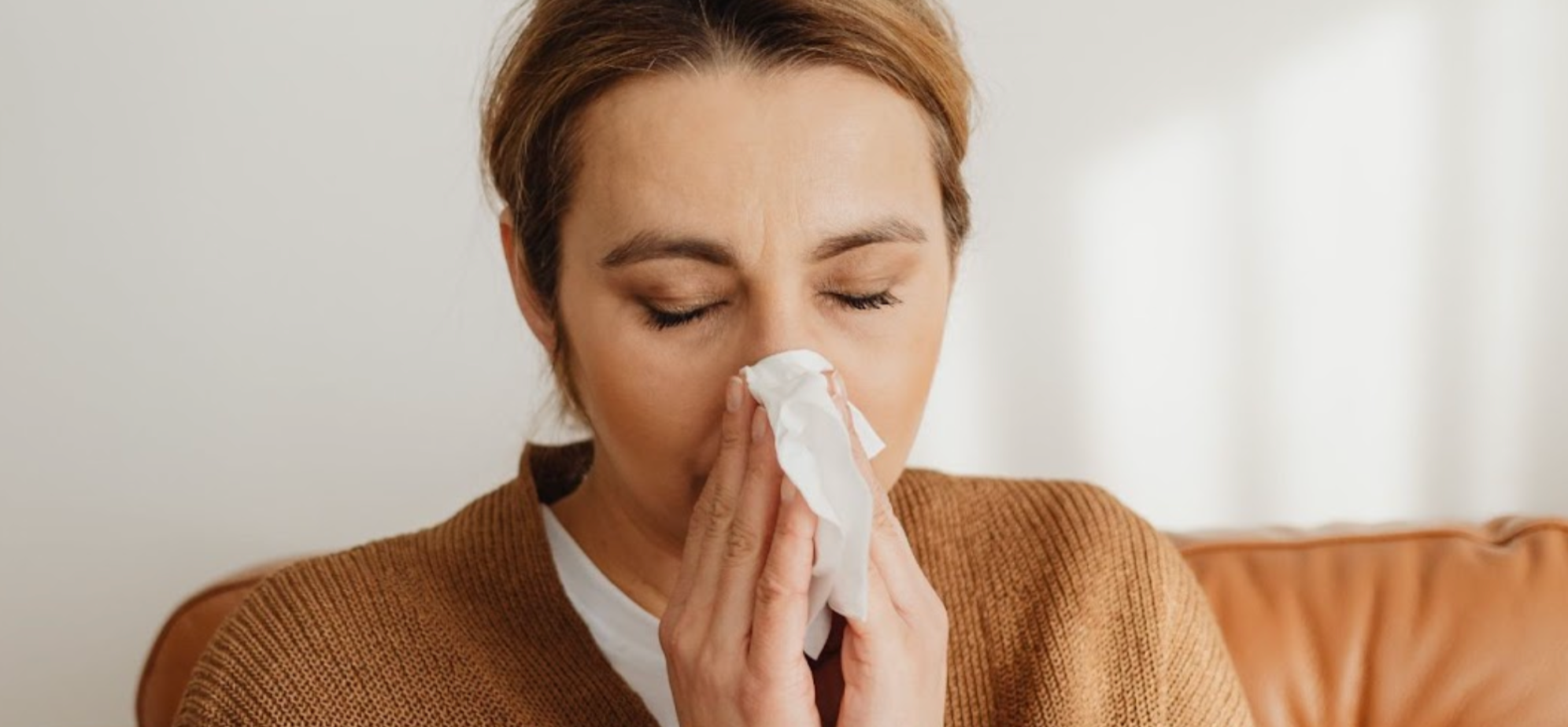 Woman blowing her nose with a tissue from a cold