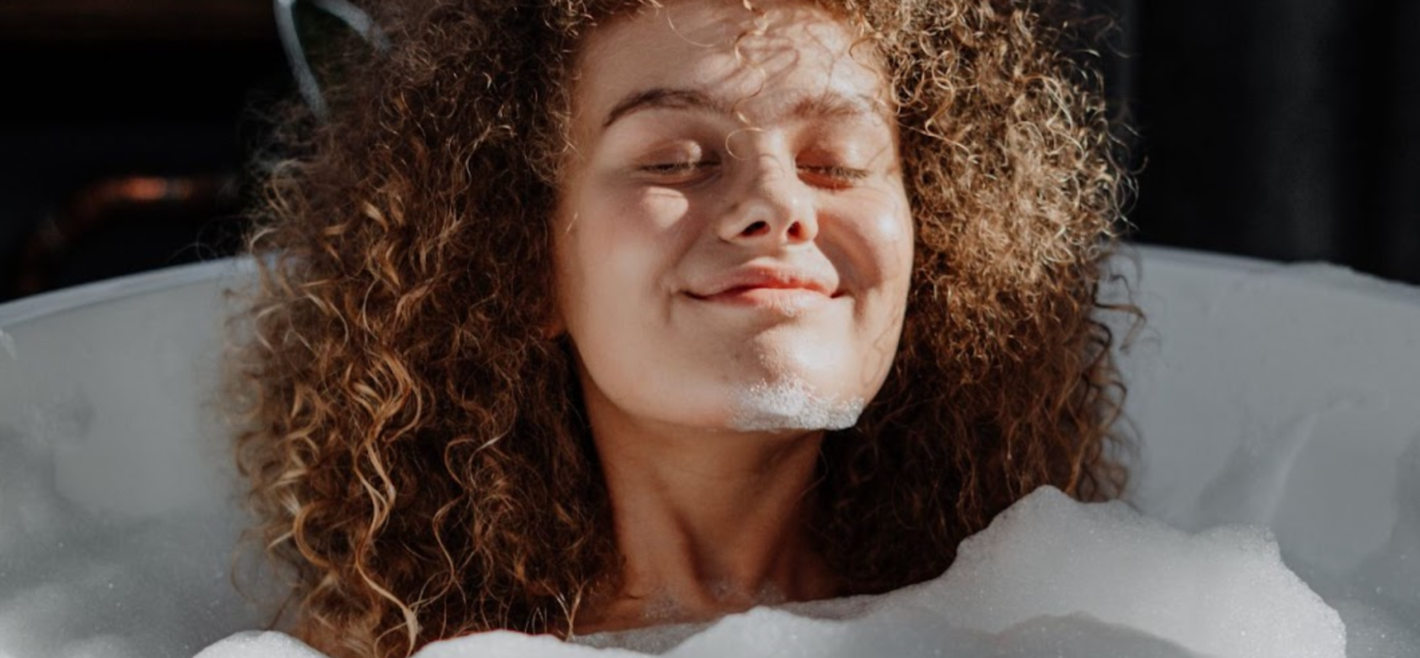 Woman relaxing and smiling in a bubble bath