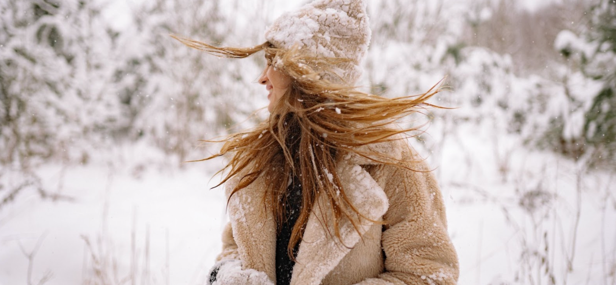 Woman in winter in a beige coat in the snow