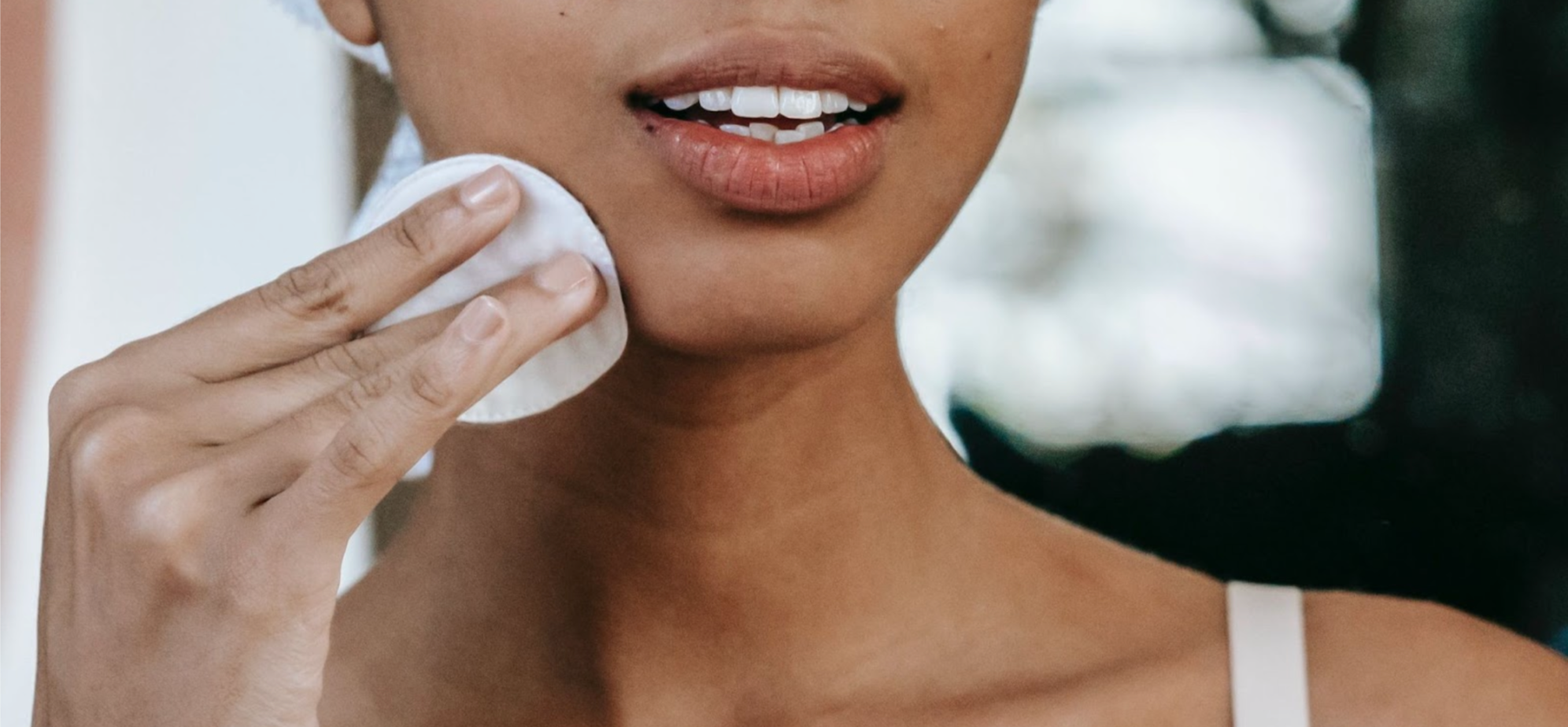 Close-up of a woman with smooth and clear skin using a makeup pad