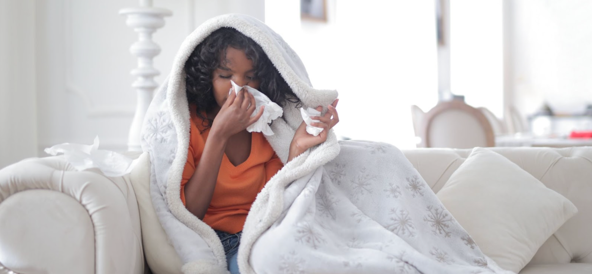 Ill woman with a cough or cold, blowing her nose on a tissue