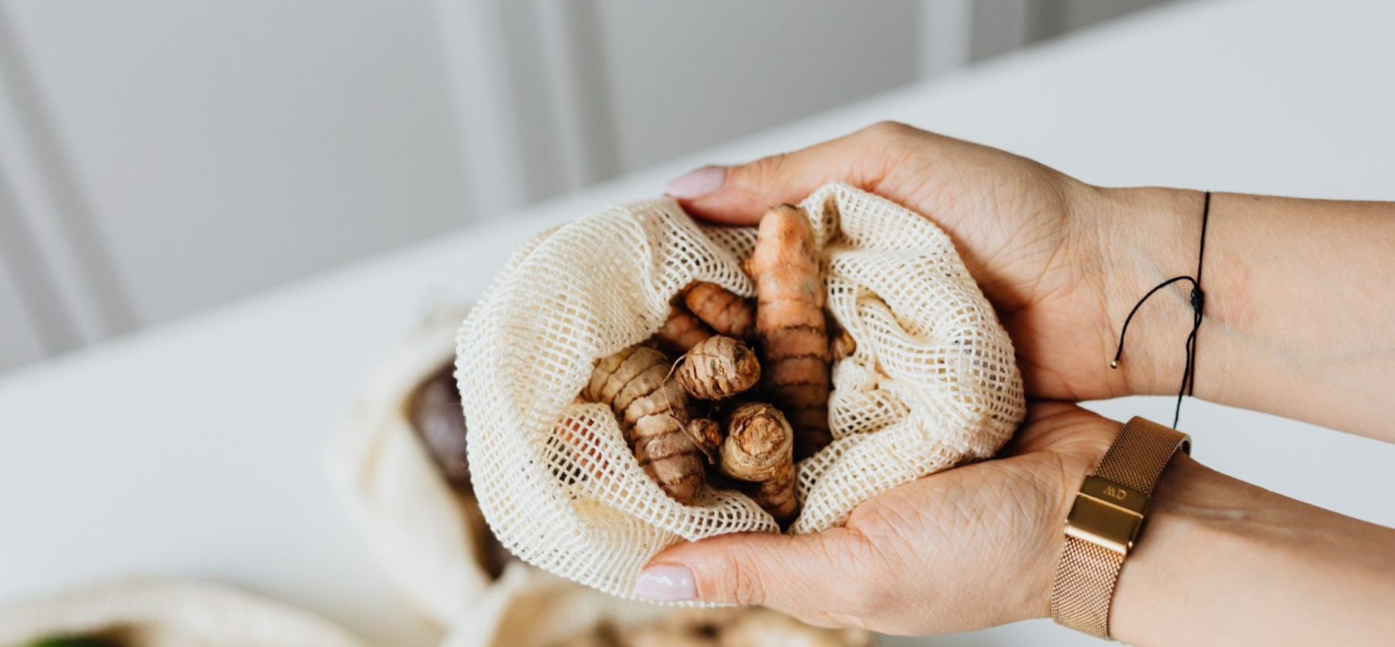 Woman holding a net bag with turmeric roots