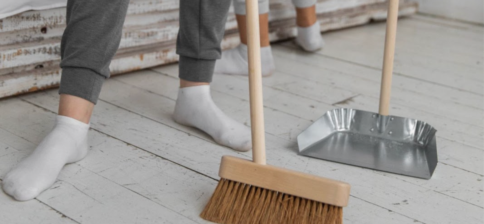 Person cleaning their home and sweeping the floors with a dustpan and brush