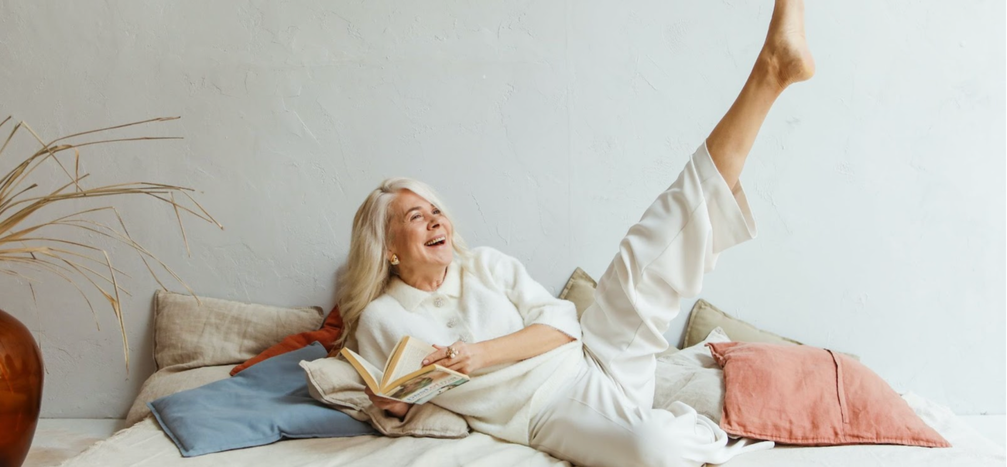 Laughing mature woman in white reading a book