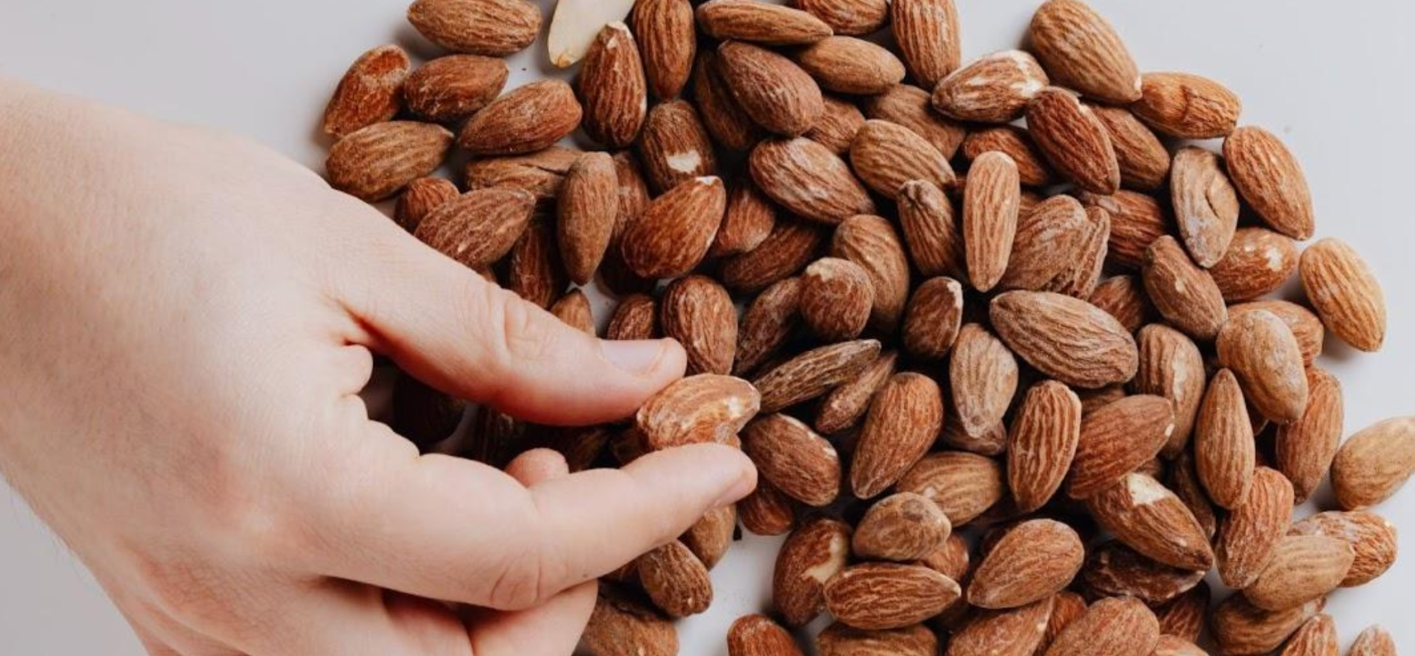 Person eating almonds as a healthy snack