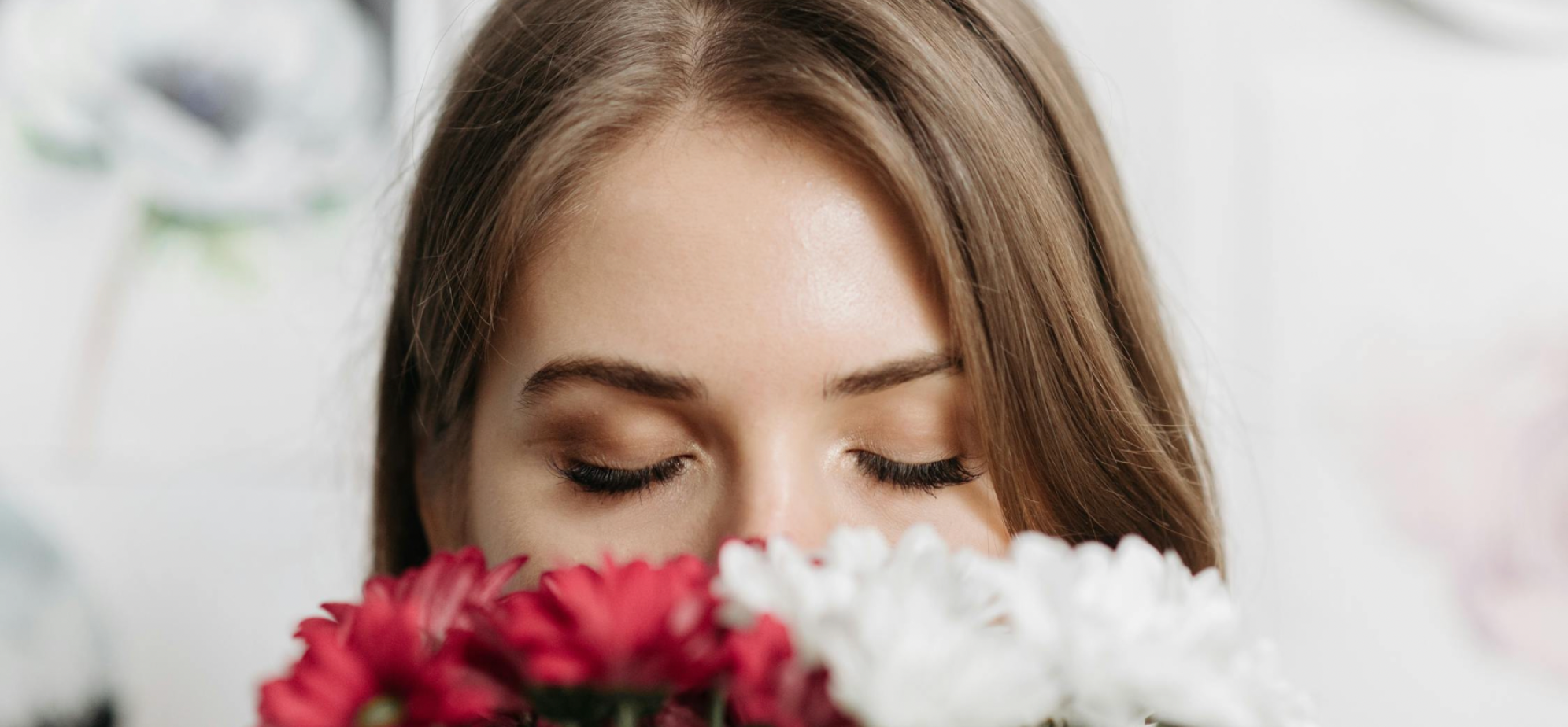 Woman smelling red and white flowers