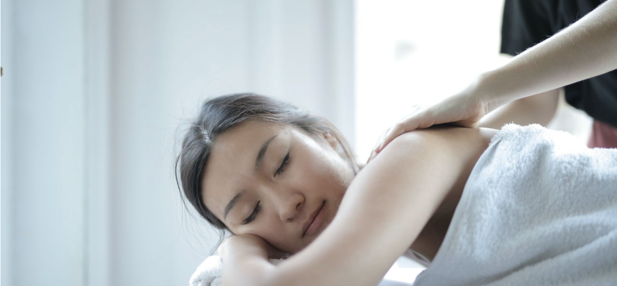 Relaxed woman with her eyes closed with her shoulders being massaged