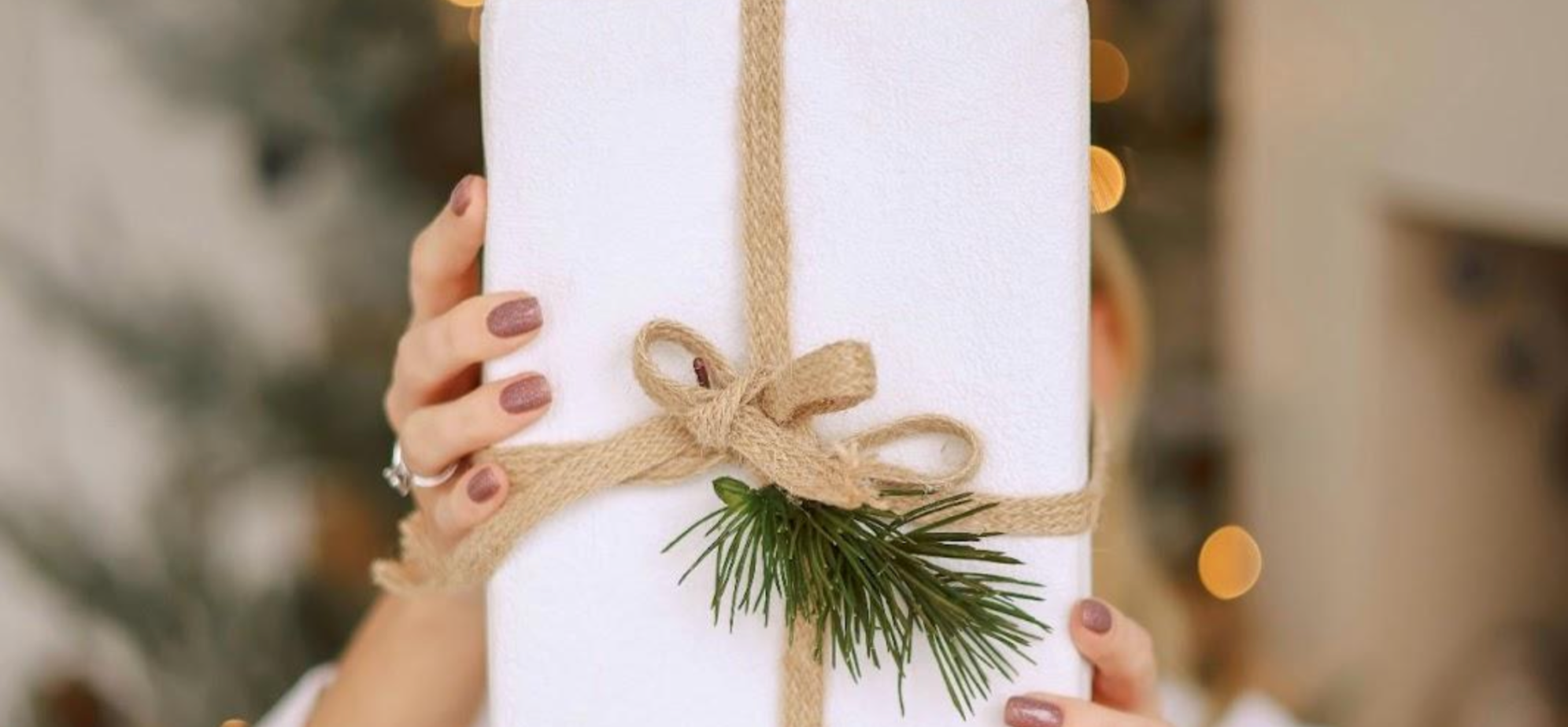 Woman holding Christmas present wrapped in natural materials for a sustainable Christmas gift