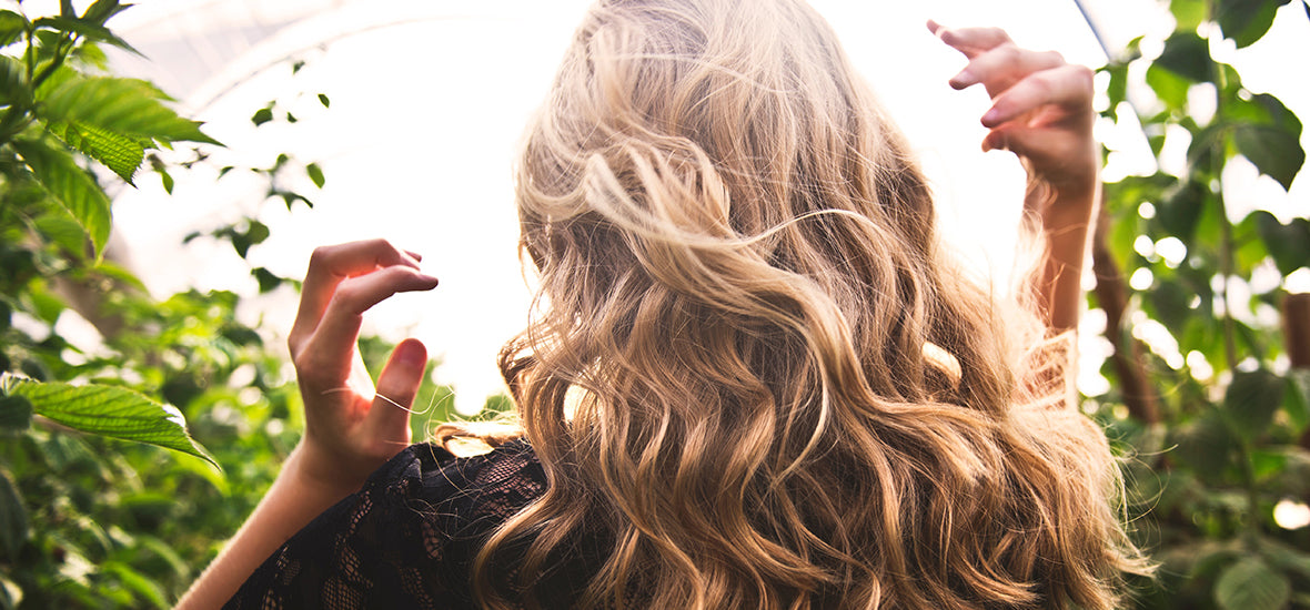 Back of woman’s head with wavy blonde hair from taking collagen for hair growth.