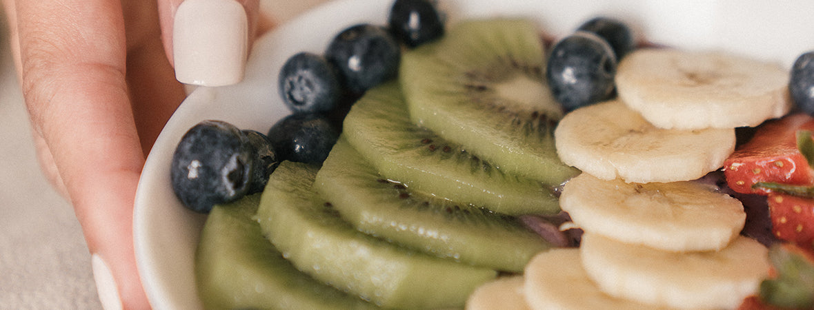 Collagen for gut health: Woman’s hand holding fruit bowl for digestion and good health.