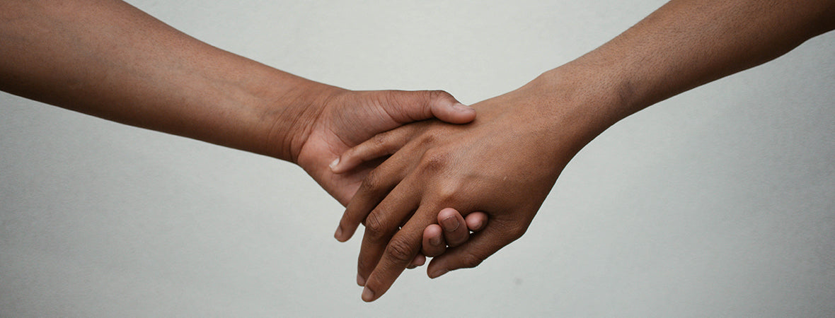 Close up of two people holding hands.