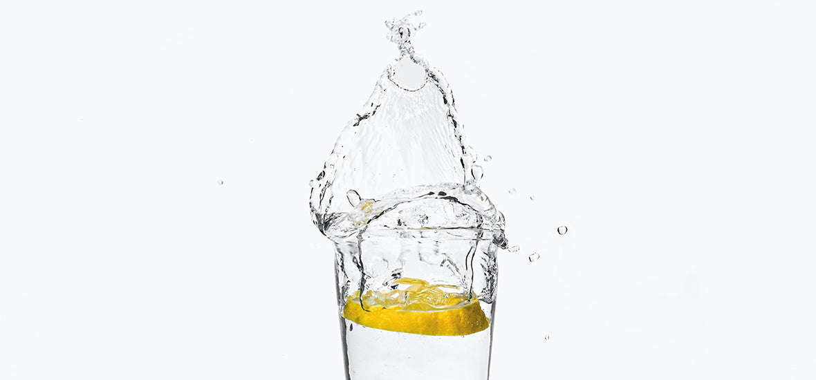 Glass with lemon slice full of water on a white background.