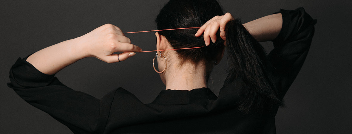 Collagen: woman stretching out rubber hairband while putting her hair in a ponytail.