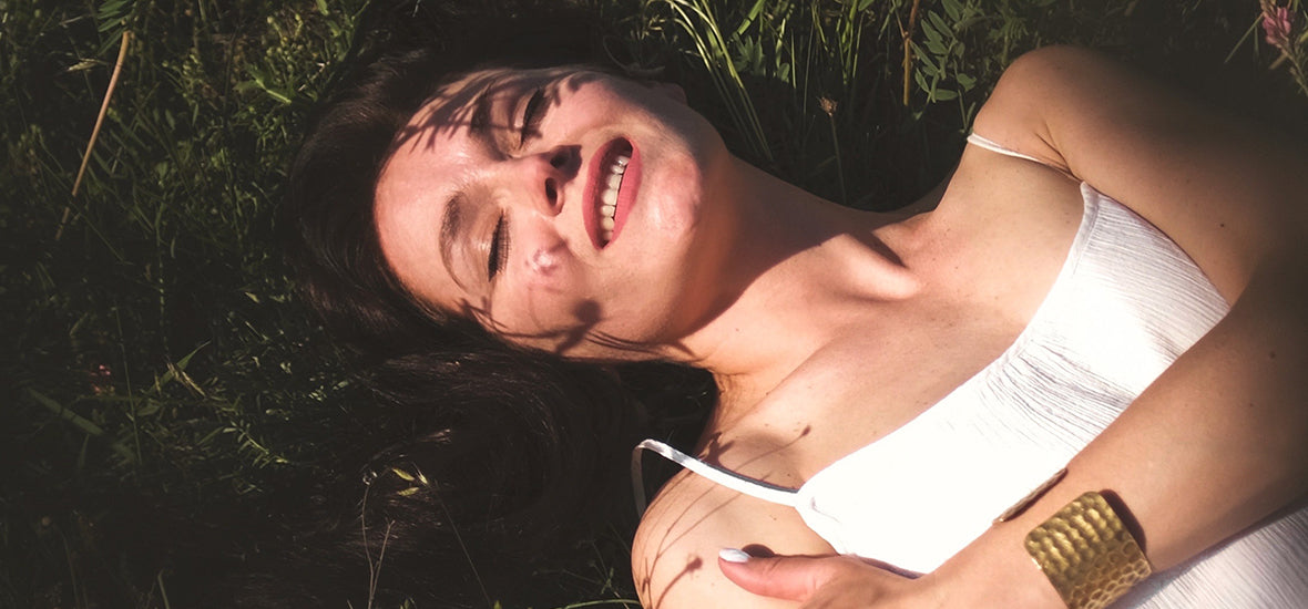 Boost collagen: Woman lying on the grass and smiling in the sun