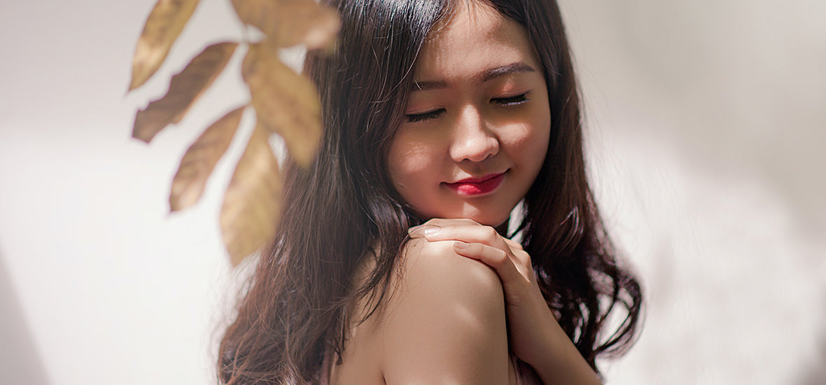 Woman with bare shoulders, red lips and glowing skin in autumn.