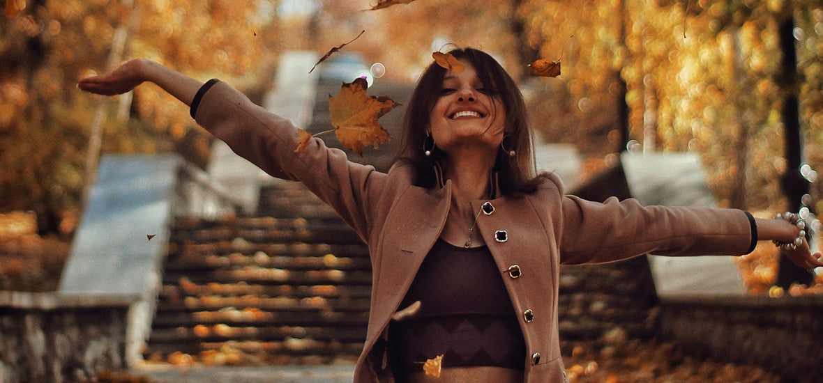 Happy, laughing woman throwing up autumn leaves.
