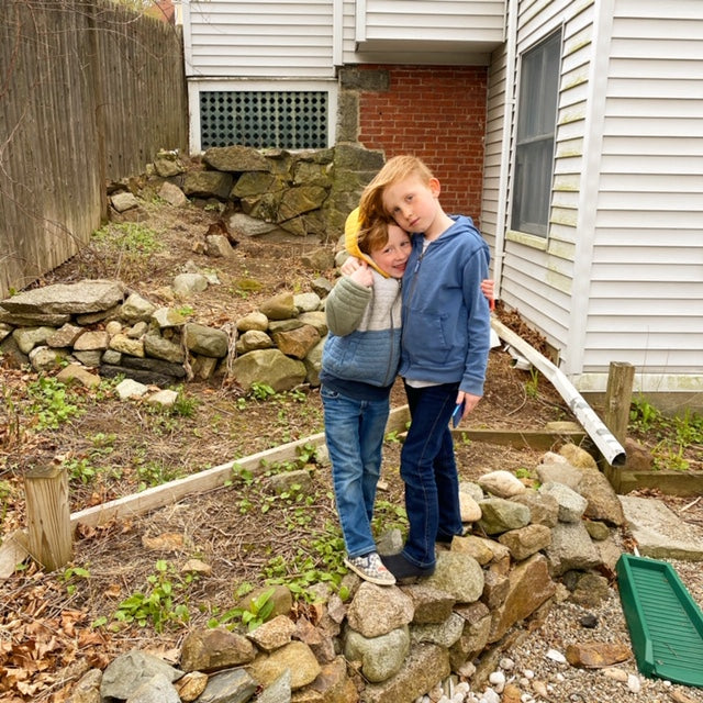 Two boys hugging by future sight of a Climate Victory Garden