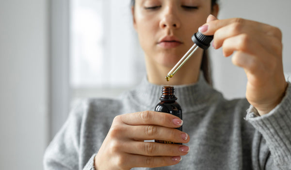 A woman taking a dose of CBD Oil from a pipette