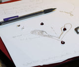 Sketch of a heart pendant, drown on a white paper with red garnet on top