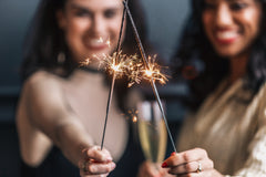 Two women holding sparkling fire stick and joining hands