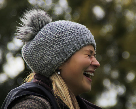 women with a grey wool cap and a coat, laughing