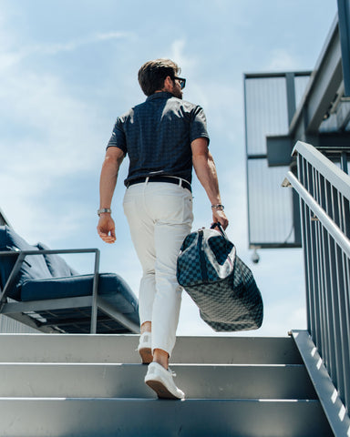 lifestyle image: man walking up stairs outside airport with luggage.