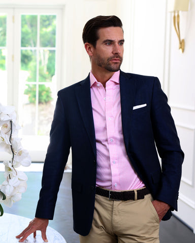 man standing in office waiting room with flowers wearing quattro flex dress shirt pink gingham and blazer and khaki ceo chinos