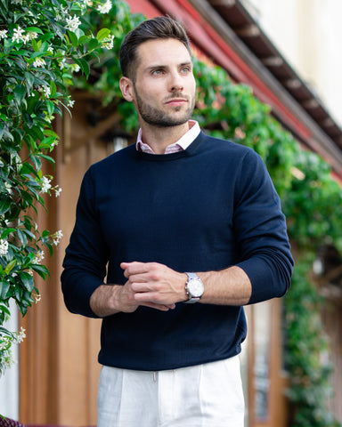 man in crew neck navy sweater and pink stripe dress shirt