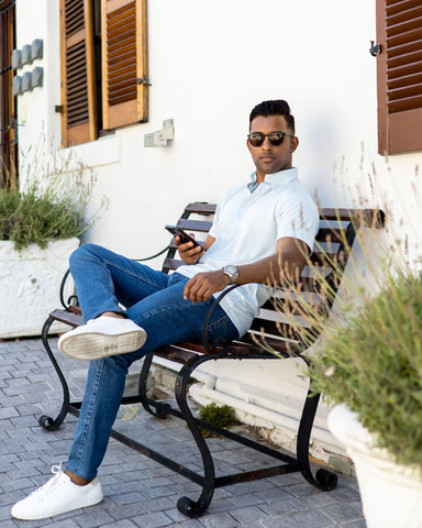 man in dress collar polo sitting on bench with phone ordering food